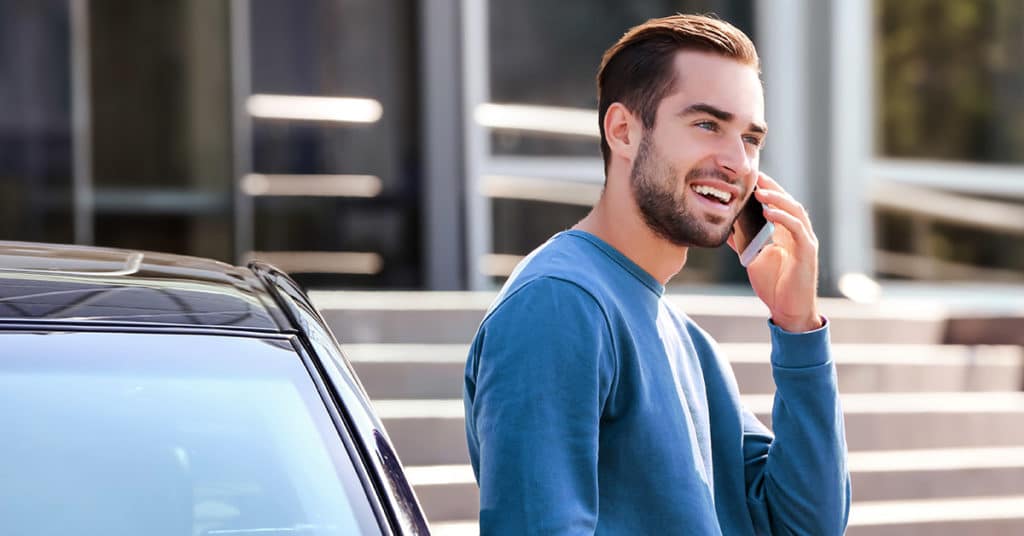 Man talking on a cell phone next to a car