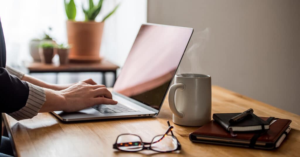 person using desk at home evoking benefits of telecommuting