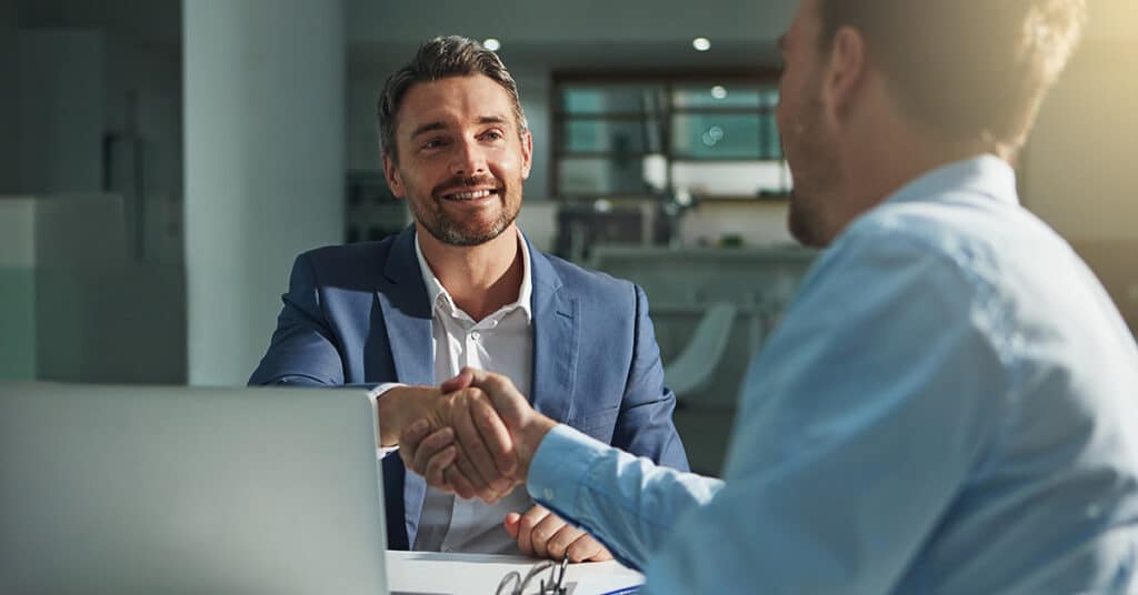 image of business men shaking hands before a computer evoking business insights