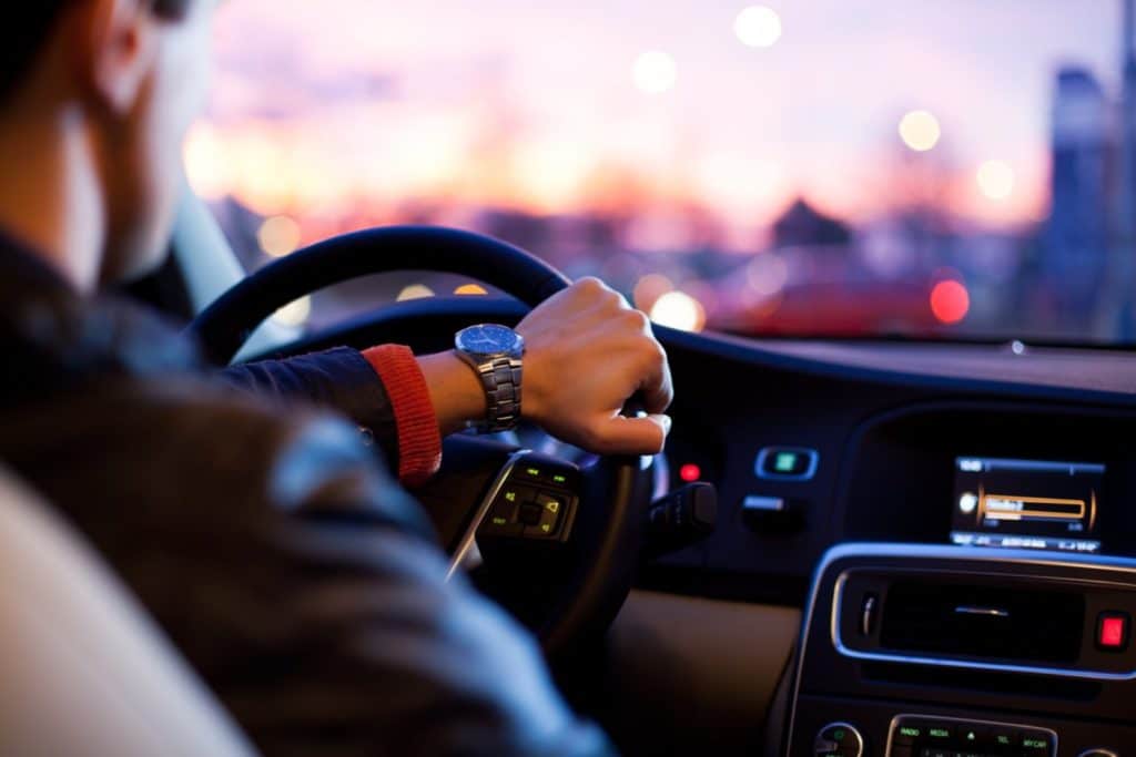 Hand with a watch resting on a steering wheel