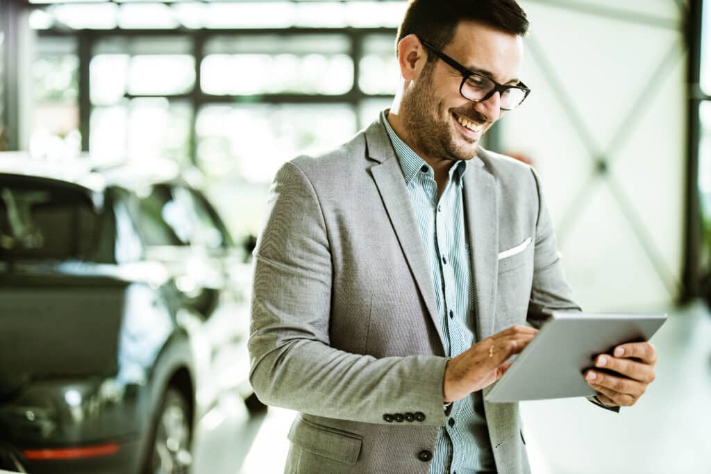 image of man reviewing ipad with car in background evoking fleet management companies