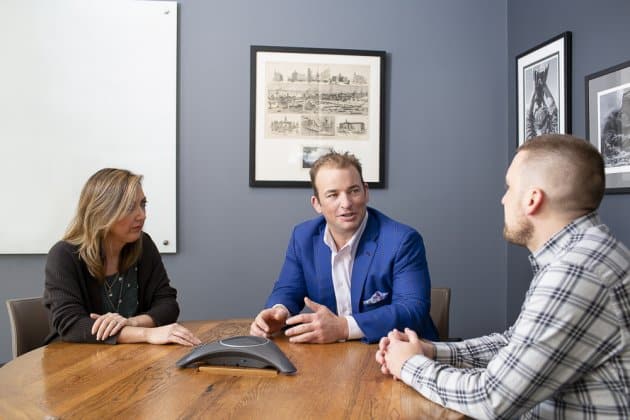 Three people sitting around a table with a speaker in the middle