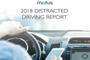 Left hand on a steering wheel and right hand holding a cell phone