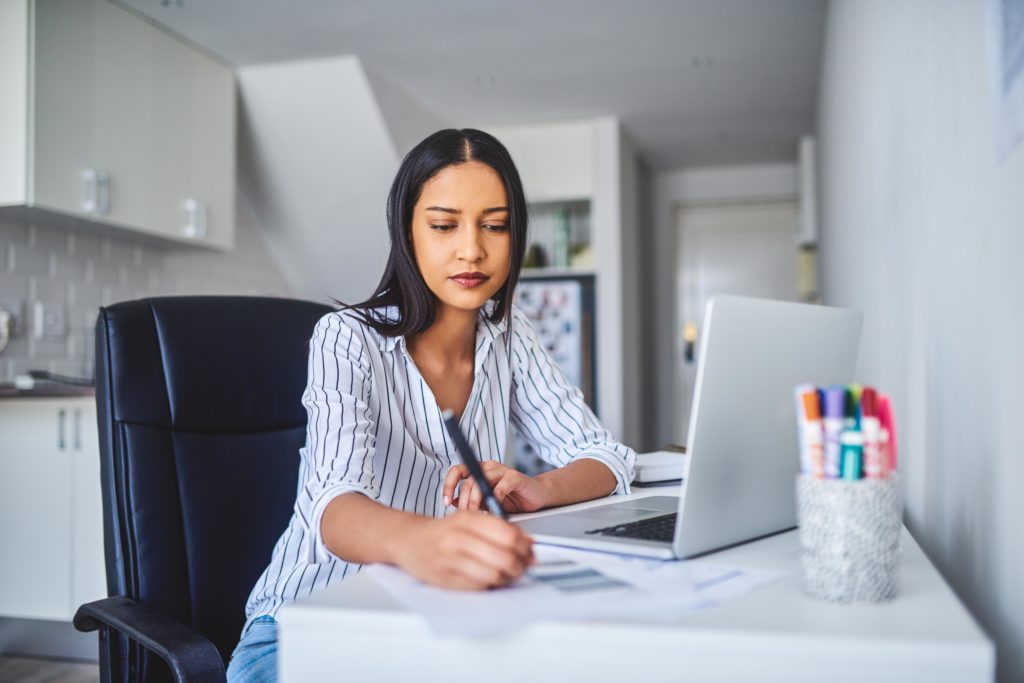 woman sitting at a desk working from home evoking Work from home reimbursement