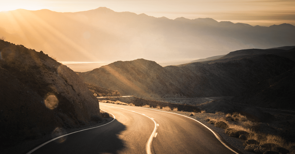 image of a mountain road during sunrise evoking 2023 IRS standard mileage rate