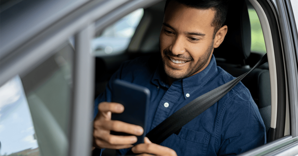 man in car using phone evoking IRS Approved Mileage Logs